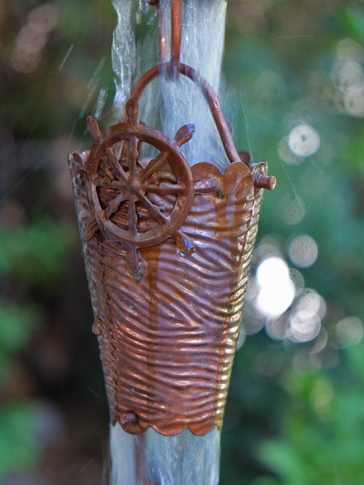 Close view of nautical copper rain chain cups with ocean wave detailing